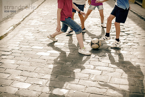 Kinder spielen mit Fußball auf der Kopfsteinpflasterstraße