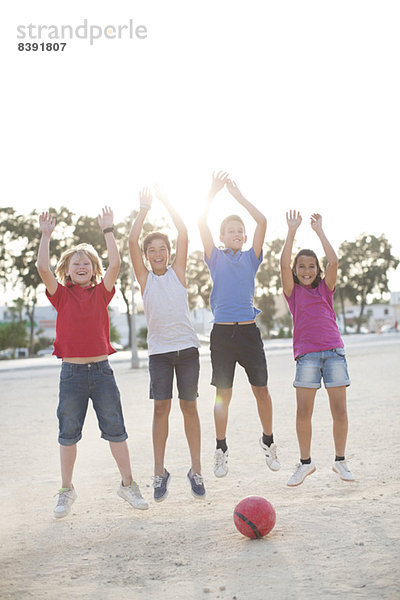 Kinder spielen mit Fußball im Sand