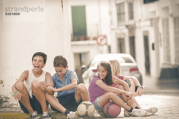 Kinder mit Fußbällen lachend auf der Stadtstraße