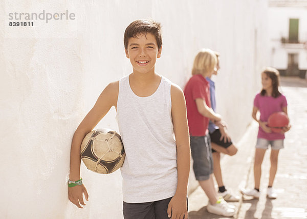 Junge hält Fußball in der Gasse