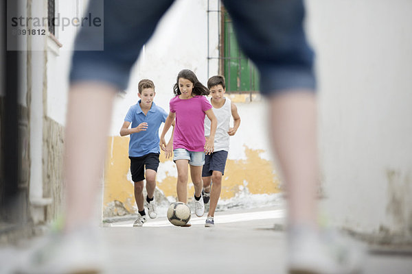 Kinder spielen mit Fußball in der Gasse