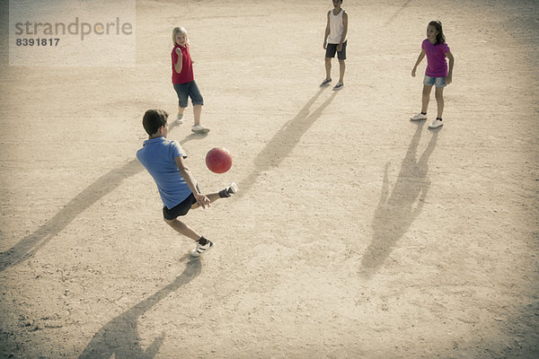 Kinder spielen mit Fußball im Sand