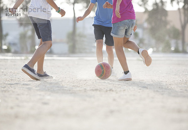 Kinder spielen mit Fußball im Sand