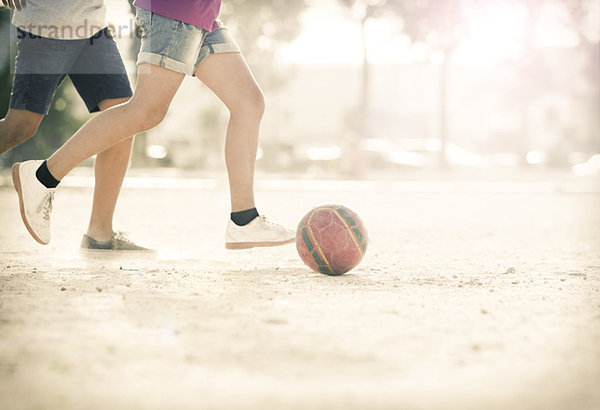 Kinder spielen mit Fußball im Sand