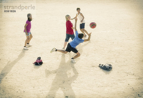 Kinder spielen mit Fußball im Sand