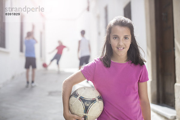 Mädchen mit Fußball in der Gasse