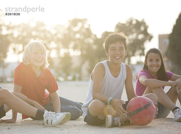 Kinder mit Fußball im Freien sitzend