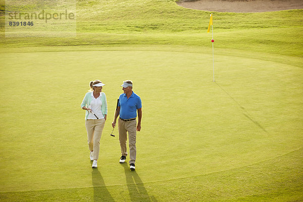 Seniorenpaar zu Fuß auf dem Golfplatz