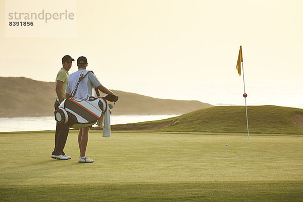 Männer auf dem Golfplatz mit Blick aufs Meer