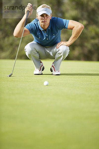 Mann  der sich darauf vorbereitet  auf dem Golfplatz zu putten.