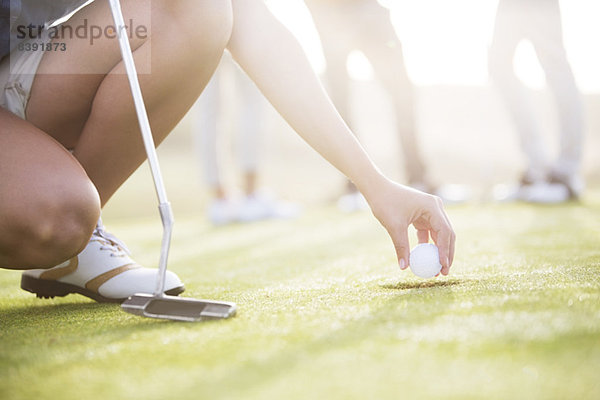 Frau entfernt Golfball aus dem Loch