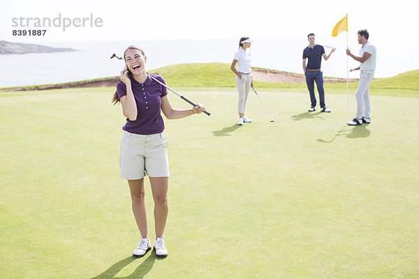 Frau beim Telefonieren auf dem Golfplatz