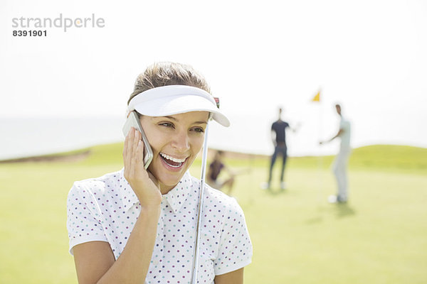 Frau beim Telefonieren auf dem Golfplatz