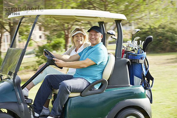 Seniorenpaar fährt Golfwagen auf dem Platz