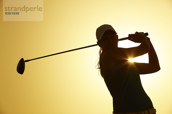 Silhouette der Golf spielenden Frau auf dem Platz