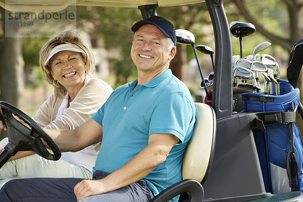 Seniorenpaar lächelt im Golfwagen