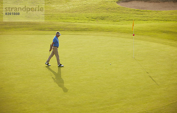 Mann  der auf dem Golfplatz spazieren geht