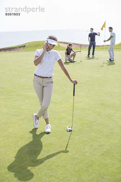 Frau beim Telefonieren auf dem Golfplatz