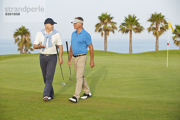 Senioren  die auf dem Golfplatz spazieren gehen