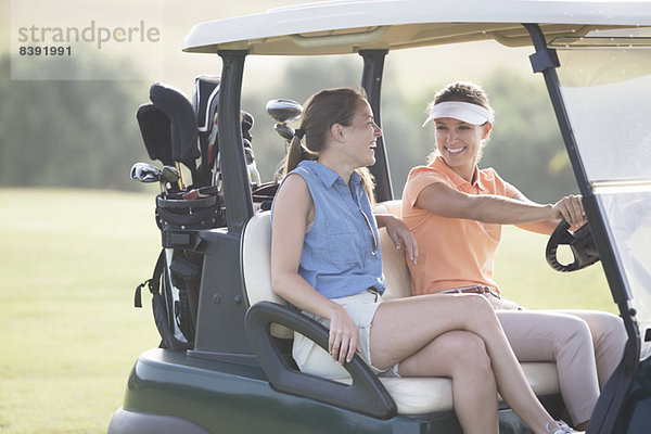 Frauen fahren Karre auf dem Golfplatz