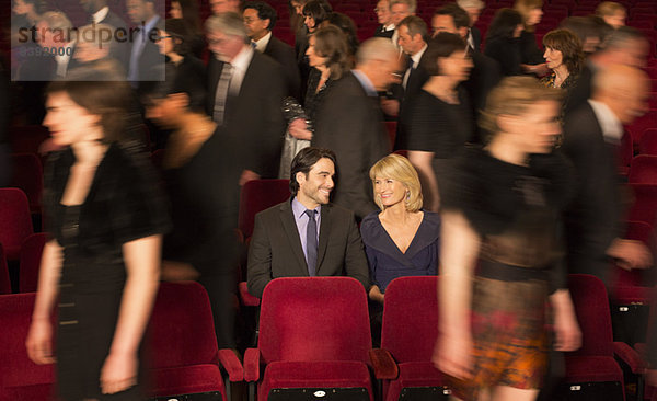 Ein Paar sitzt zwischen Menschen  die das Theater verlassen.