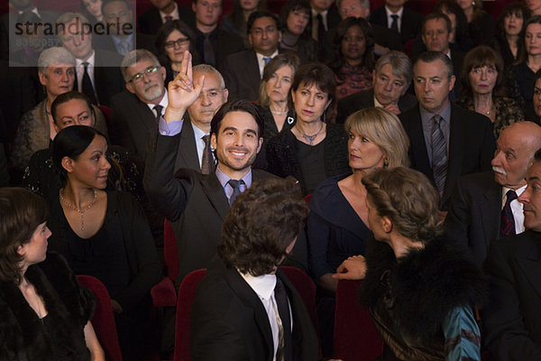 Mann hebt die Hand im Theaterpublikum