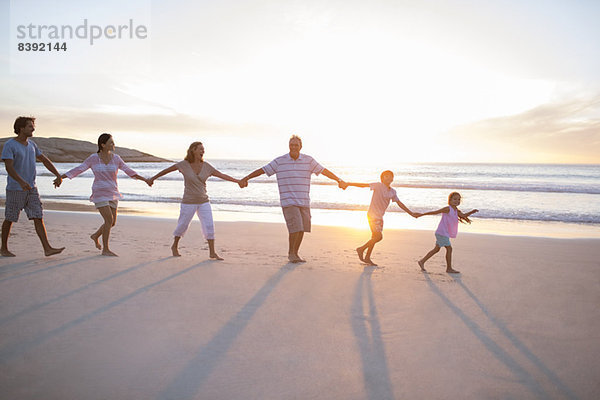 Familie hält Hände am Strand
