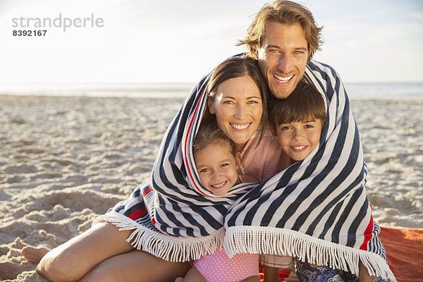 Familie in Decke gehüllt am Strand
