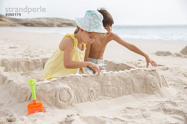 Kinder machen Sandburg am Strand