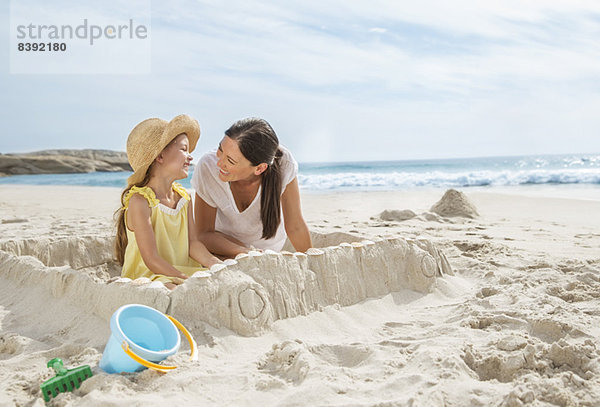 Mutter und Tochter machen Sandburg am Strand