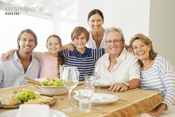 Mehrgenerationen-Familie lächelt gemeinsam bei Tisch
