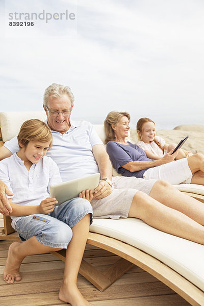 Großeltern und Enkelkinder mit digitalen Tabletts am Pool