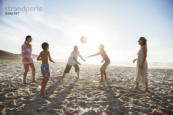 Mehrgenerationen-Familie beim Volleyball am Strand