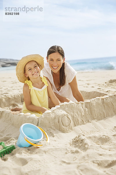Mutter und Tochter machen Sandburg am Strand