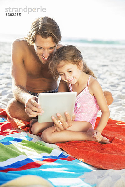 Vater und Tochter mit digitalem Tablett am Strand