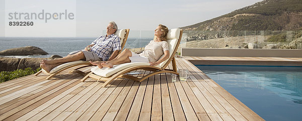 Älteres Paar entspannt sich in Liegestühlen am Pool