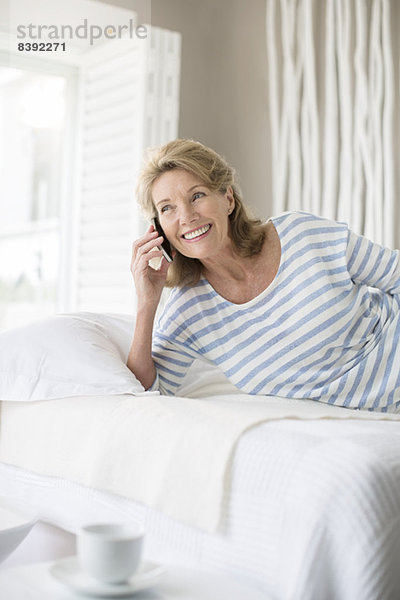 Ältere Frau beim Telefonieren im Bett