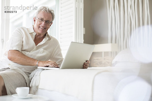 Älterer Mann mit Laptop im Bett