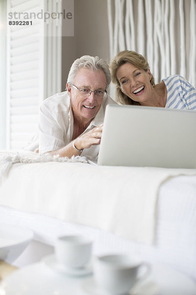 Älteres Paar mit Laptop im Bett