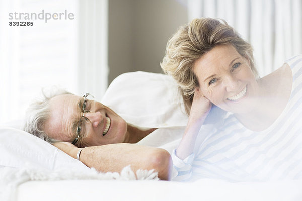 Älteres Paar lächelt auf dem Bett