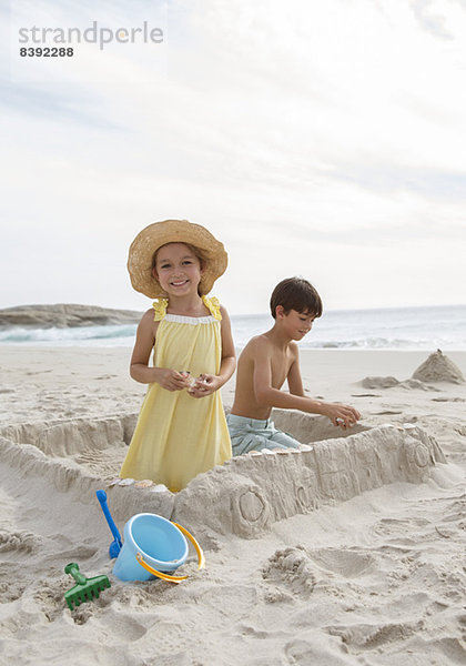 Kinder bauen Sandburg am Strand