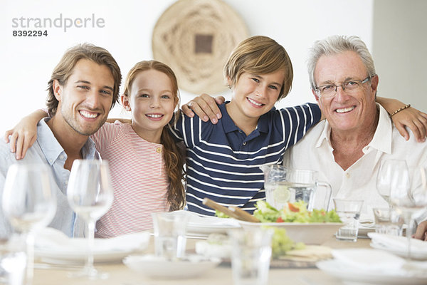 Familie lächelt gemeinsam bei Tisch