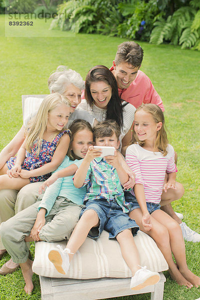 Familie  die zusammen im Garten ein Handy benutzt