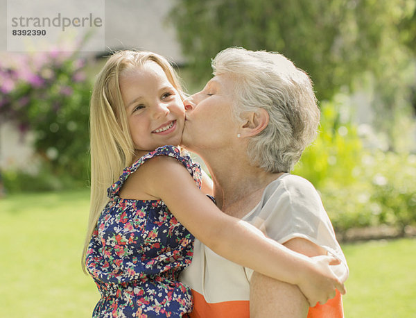 Ältere Frau küsst Enkelin im Freien