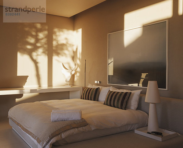 Spiegelung von Bäumen an der Wand im modernen Schlafzimmer
