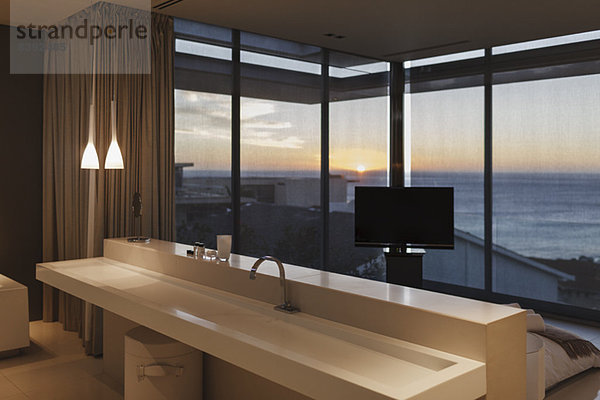 Modernes Waschbecken im Schlafzimmer mit Blick auf das Meer bei Sonnenuntergang