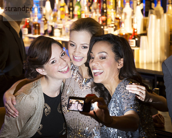 Lächelnde Frauen beim Umarmen und Selbstportraitieren im Nachtclub
