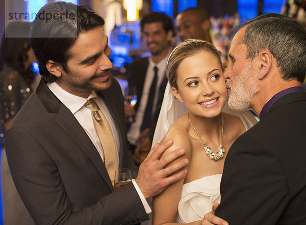 Vater küsst Brautwange beim Hochzeitsempfang