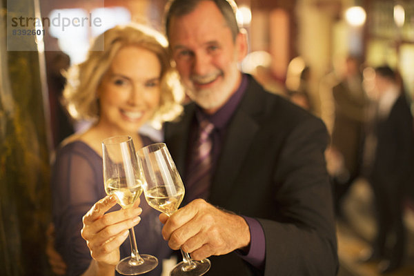 Porträt eines gut gekleideten Paares  das in der Theaterlobby auf Champagnergläser anstößt