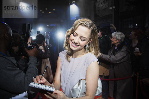 Gut gekleidete weibliche Berühmtheit gibt Autogramme beim Red Carpet Event